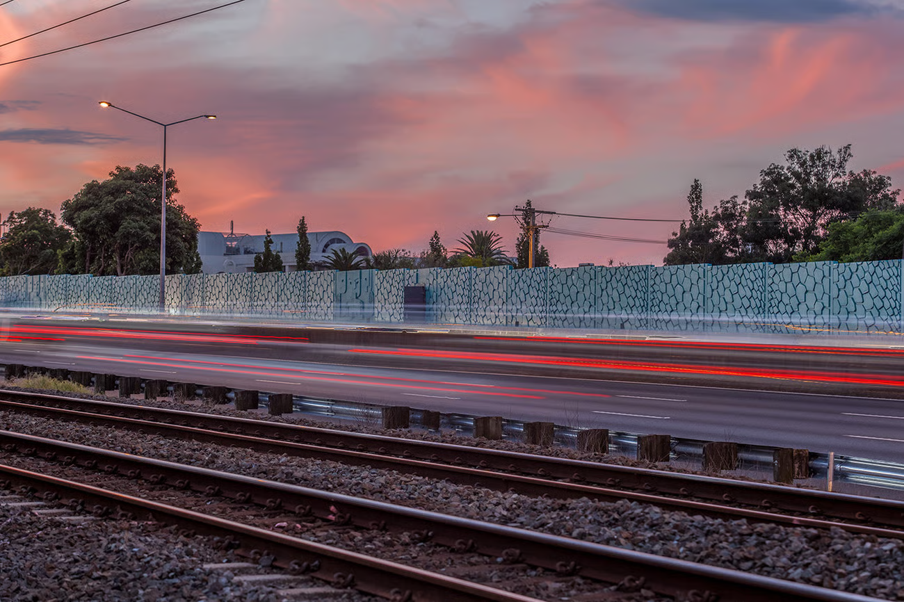 Urban rail corridor at dusk with a planted embankment